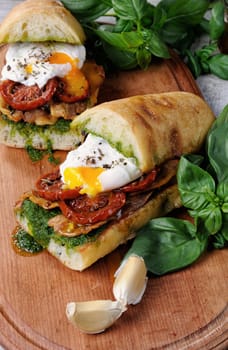 Toasted ciabatta with pesto, slices of bacon, sun-dried tomatoes and poached egg