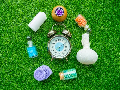Alarm clock and accessories of spa scrub for skin healthy on green lawn background.
