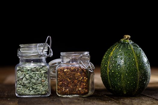 Tasty pumpkin and spices on a wooden kitchen table, black background