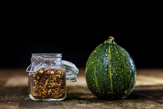 Tasty pumpkin and spices on a wooden kitchen table, black background