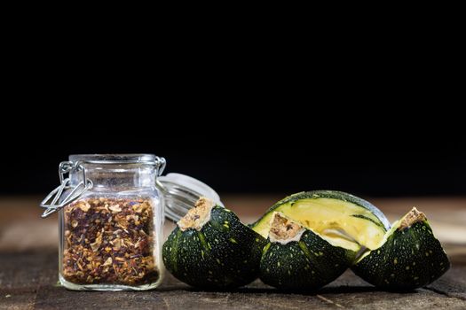 Tasty pumpkin and spices on a wooden kitchen table, black background