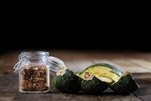 Tasty pumpkin and spices on a wooden kitchen table, black background