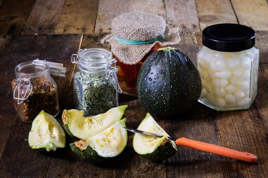 Pumpkin jars and spices. Preparations from your own garden. Wooden kitchen table. Black background.