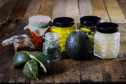 Pumpkin jars and spices. Preparations from your own garden. Wooden kitchen table. Black background.