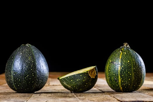 Tasty mini pumpkin on a wooden table, black background