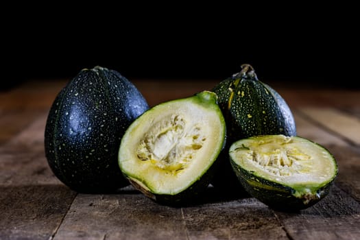 Tasty mini pumpkin on a wooden table, black background