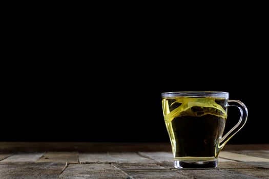 Tasty tea with nettles on a wooden table, black background