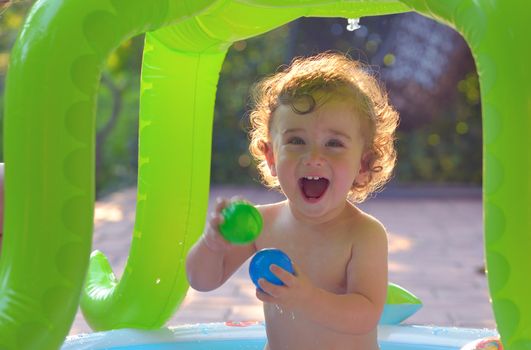 Laughing little girl play in the small pool 