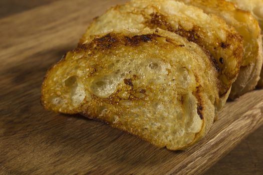 Grilled slices of French bread on a wooden board