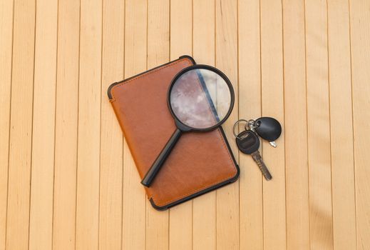 Magnifying glass e-book and keys on wooden background