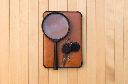 Magnifying glass e-book and keys on wooden background