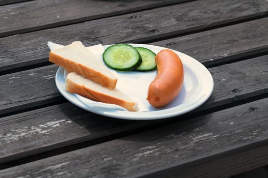 Bock sausage, wieners or Frankfurther sausage with toast and cucumbers on a white plate.