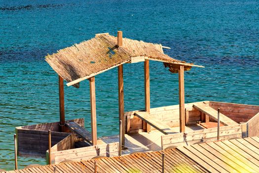 Boat bridge with simple boat house or wooden boat with thatched roof.