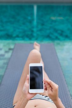Woman with bikini using mobile phone in swimming pool
