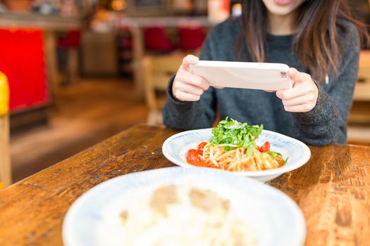 Woman taking photo on dish in coffee shop