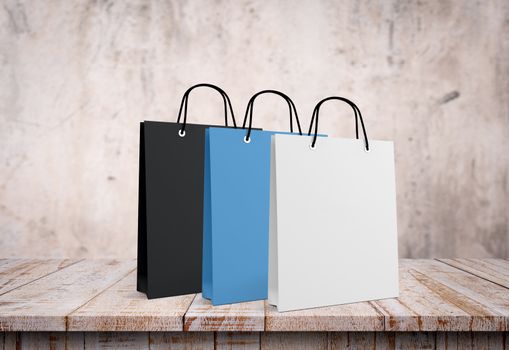 Three paper bags for shopping on a wooden background