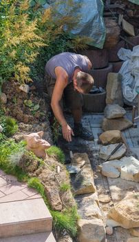 Man Build a dry wall in the garden. In the background, various tools.