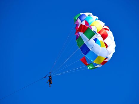 Parasailing with colorful parachute in clear blue sky popular vacation activity in summer resorts