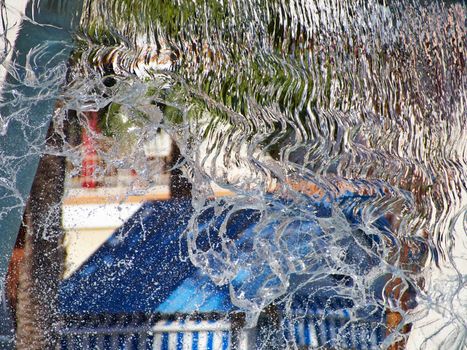 Water jet in a city park fountain with blurred out of focus  background