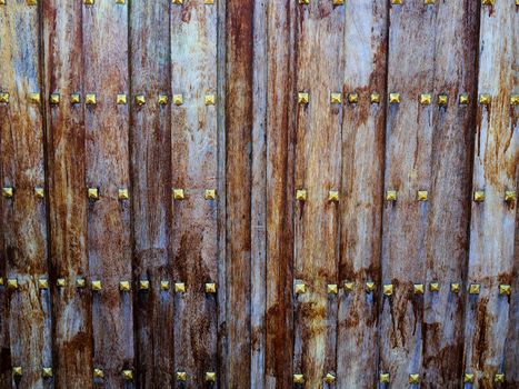 Ancient vintage old style heavy wooden door gate with metal decorations