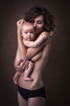 Young mother holding a baby in her arms. Studio shot