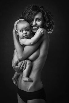 Young mother holding a baby in her arms. Studio shot