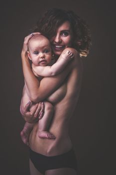 Young mother holding a baby in her arms. Studio shot