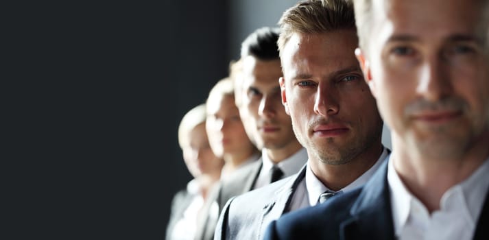 Serious business team standing in a row at office, gray copy space