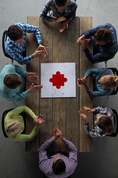 Business people and puzzle on wooden table, teamwork concept