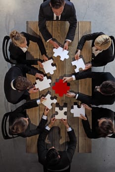 Business people and puzzle on wooden table, teamwork concept