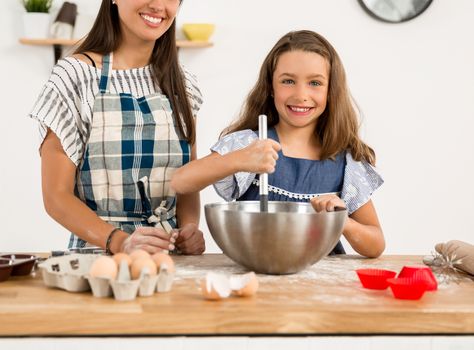 Shot of a mother and daughter having fun in the kitchen and learning to make a cake