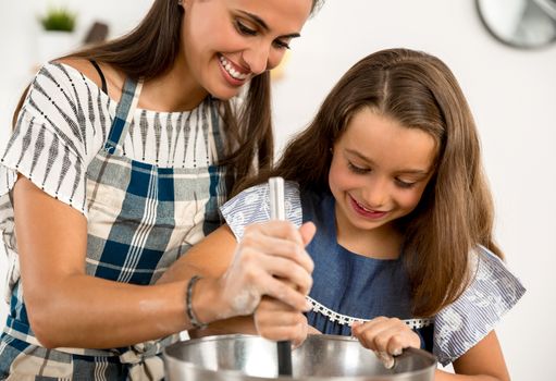 Shot of a mother and daughter having fun in the kitchen and learning to make a cake