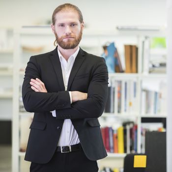 Portrait of hansome redhead bearded business man in office keeping arms crossed and looking at camera