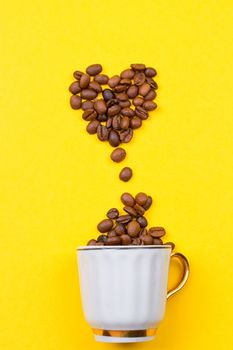 A cup of coffee and heart of the beans on yellow background