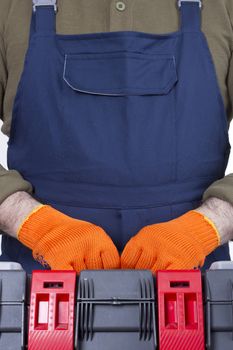 Hands of the worker in orange gloves with a tool box