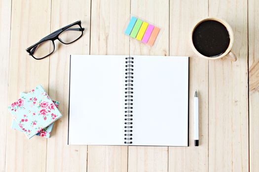 Still life business office supplies or education concept : Top view of working desk with blank notebook with pen, coffee cup, colorful note pad and eyeglasses on wooden background