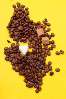 Coffee beans and sugar in the form of heart on a yellow background