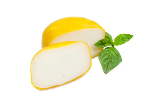 Small wheel of the Dutch firm goat cheese cut into two parts and twig of green basil on a white background
