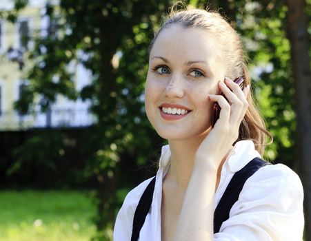 Closeup shot of young smiling woman speaks by a mobile phone