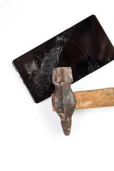 An old hammer and smartphone with broken screen on a white background