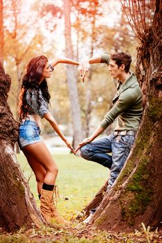 Beautiful lovely couple enjoying in sunny park in autumn colors and with their hands making a heart shape.