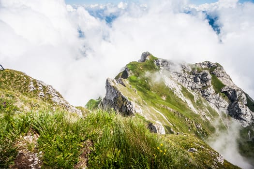 Great Majestic Dreamy Landscape View of Natural Swiss Alps from Mount Pilatus Peak. Breathtaking view of Steep Cliff surrounded with creeping fog and cloud.