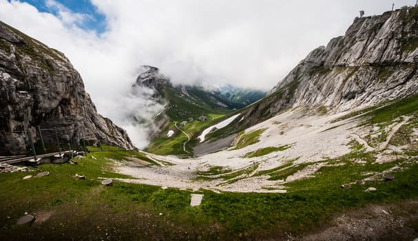Great Majestic Dreamy Landscape View of Natural Swiss Alps from Mount Pilatus Peak. Breathtaking view of Steep Cliff surrounded with creeping fog and cloud.