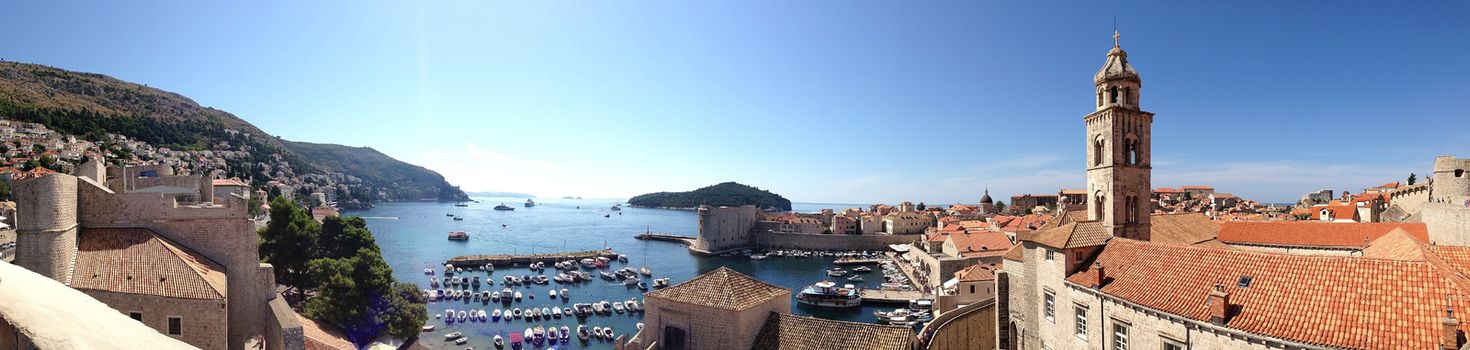 Classic panoramic view of traditional Mediterranean Old Town houses with red tiled roofs, dock and picturesque island in background, Dubrovnik, Dalmatia, Croatia, Europe.