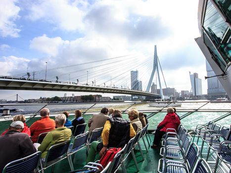 ROTTERDAM, NETHERLANDS - SEP 03, 2016: Tourists on the Spido boat tours looking up Erasmus Bridge in Rotterdam. It offers tours around one of the largest ports in the world It operates for over 80 years and has over 400,000 passengers per year.
