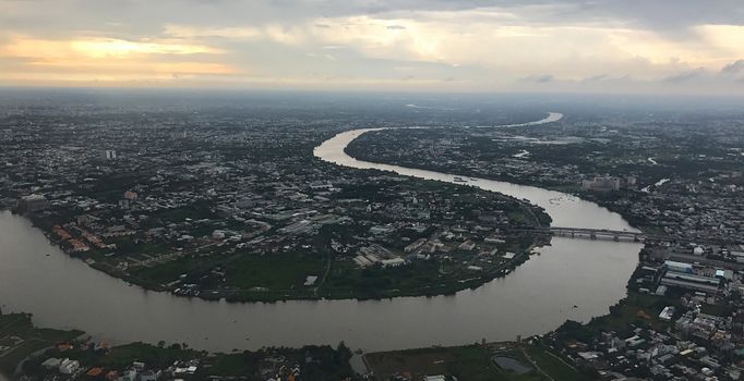 Bird eye view from plane window: Ho Chi Minh City with meandering Saigon River at dusk on a rainy day