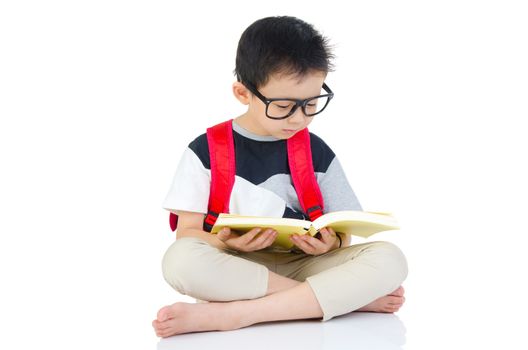 Asian preschool boy with schoolbag and books sitting on the floor