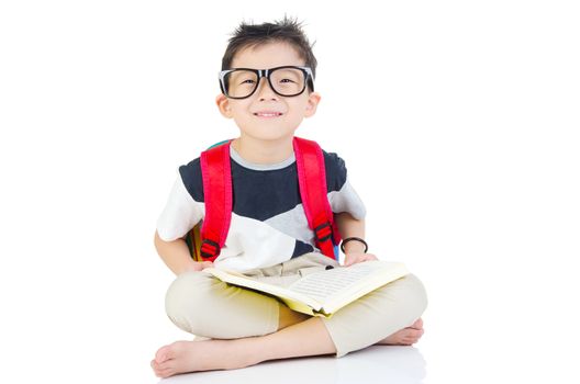 Asian preschool boy with schoolbag and books sitting on the floor