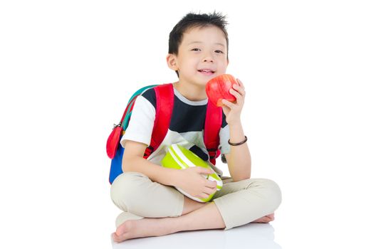 Asian primary school boy holding lunch box and apple. Healthy eating concept for schoolchild.