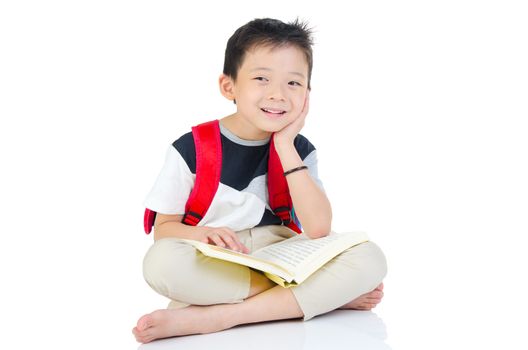 Asian preschool boy with schoolbag and books sitting on the floor